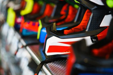 A row of motorcycle helmets on the shelf in the store.