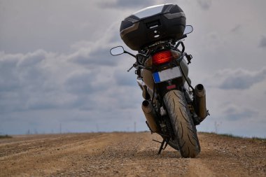 Enduro motorcycle traveler alone under a blue sky with white clouds.