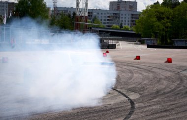 Yarış arabası hız yolunda sürükleniyor, profesyonel sürücü yarış pistinde dumanla sürükleniyor, soyut doku ve arka planda siyah lastik izleri asfalt yolda kayıyor, tekerlek izleri var..
