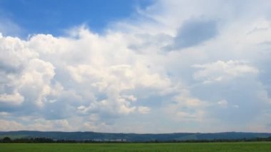 Bahar cumulus bulutları otsu çayır üzerinde.