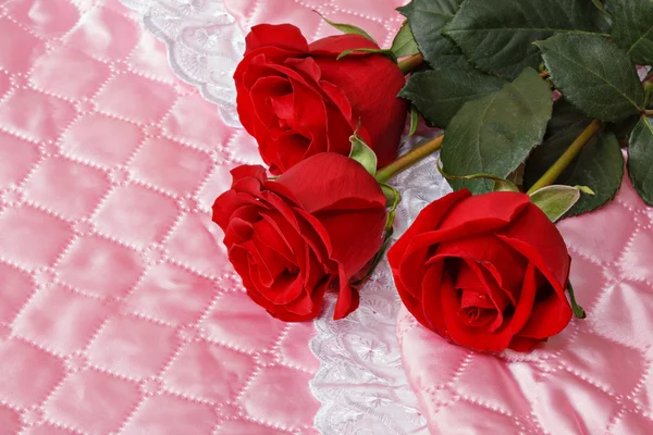 Czerwone róże na różowy satyna. — Zdjęcie stockowe
