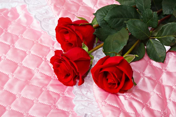 Trandafiri rosii pe satin roz . — Fotografie, imagine de stoc