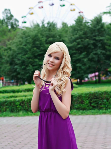 Portrait of a beautiful young woman in a violet dress in park