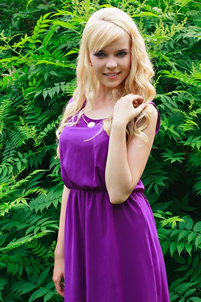 Egy lila ruhát parkban egy gyönyörű fiatal nő portréja — Stock Fotó