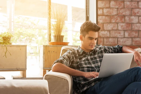 Businessman using laptop on sofa in coffee shop — Stock Photo, Image