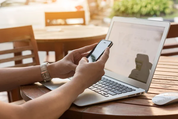 Hombre usando smartphone y portátil en mesa de madera — Foto de Stock