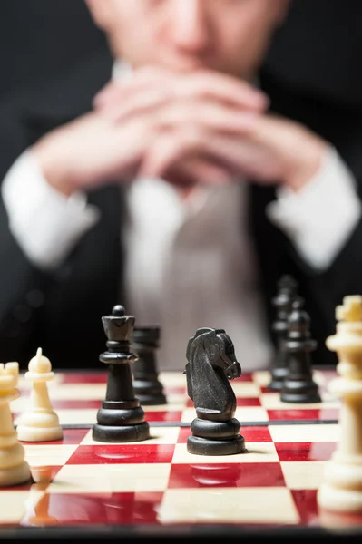 Adam satranç oynamaktan beyaz gömlek siyah takım elbise üzerinde düşünmek için strateji b — Stok fotoğraf