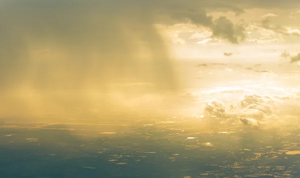 Птичий взгляд на небо с солнечным светом, облаком и дождём в городе — стоковое фото