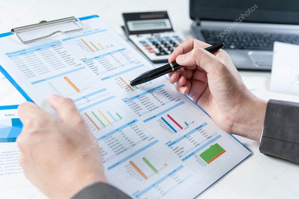 Businessman analyzing report on chart with laptop and calculator