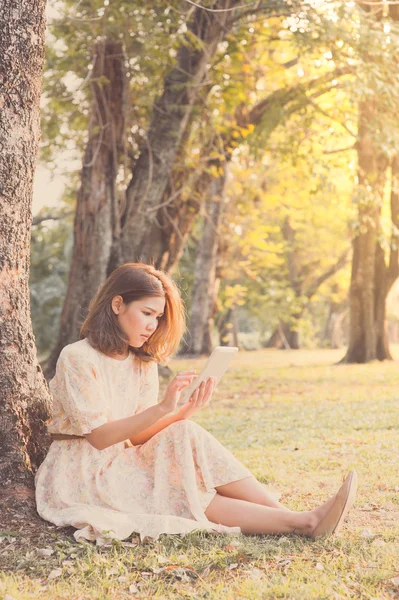 Pretty girl playing electronic pad in park, vintage style — Stock Photo, Image