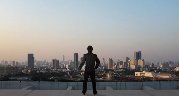 Pengusaha berdiri di atap gedung pencakar langit, konsep bisnis — Stok Foto