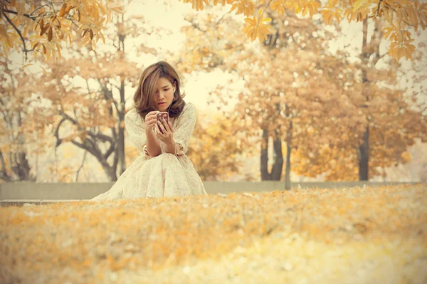 Schöne junge Frau spielt Smartphone im Park — Stockfoto