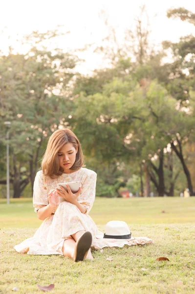 Jovem mulher usando tablet no parque — Fotografia de Stock