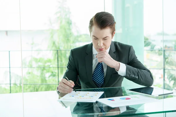 Бизнесмен в черном костюме использовать планшет и читать отчет в офисе — стоковое фото