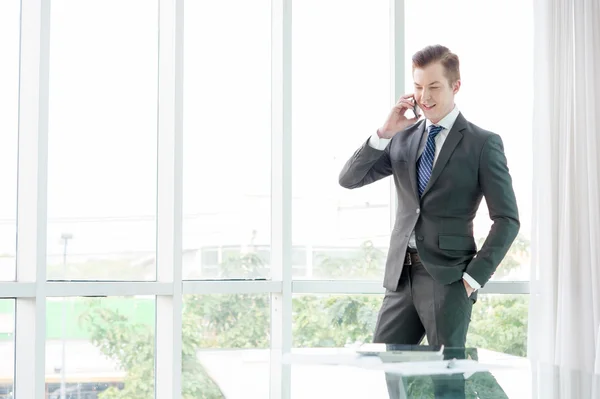 Bell'uomo d'affari in giacca e cravatta che parla al telefono in ufficio — Foto Stock
