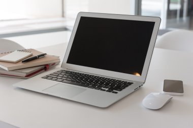 Çalışma masasında kitap ve akıllı telefon olan dizüstü bilgisayar.