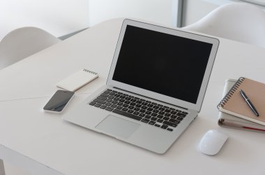 Çalışma masasında kitap ve akıllı telefon olan dizüstü bilgisayar.