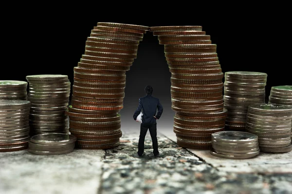 Man standing in front of giant coin pile, business concept — Stock Photo, Image