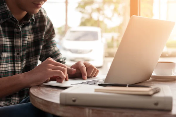 Businessman using laptop with tablet and pen on wooden table in