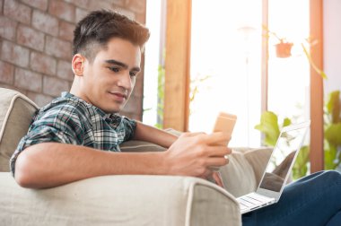 Smartphone ve kahve kanepe üzerinde yazma dizüstü kullanarak iş adamı
