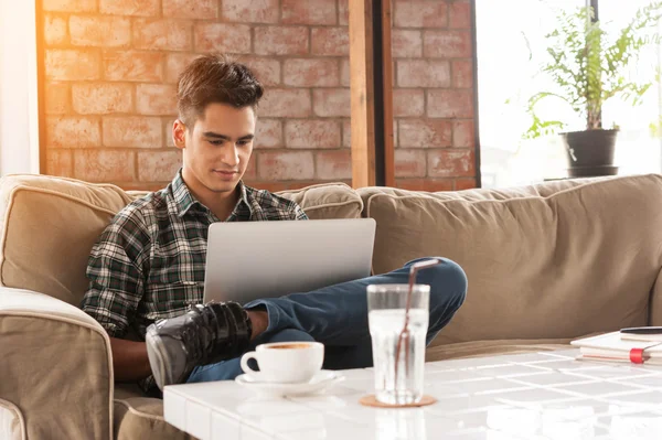 Бізнесмен використовує ноутбук на дивані в кав'ярні з чашкою ко — стокове фото