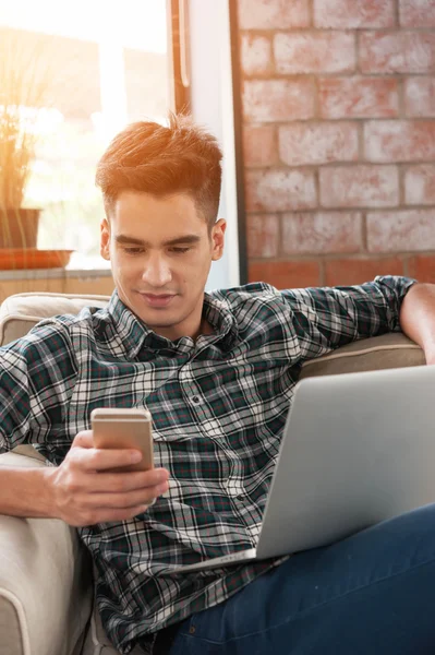 Smartphone ve kahve kanepe üzerinde yazma dizüstü kullanarak iş adamı