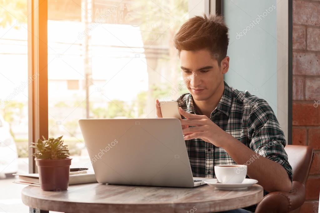 Businessman using smartphone and laptop with tablet and pen on w