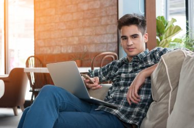 Smartphone ve kahve kanepe üzerinde yazma dizüstü kullanarak iş adamı