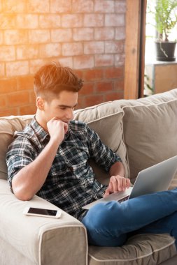 Divan kafede dizüstü ve smartphone kullanarak iş adamı