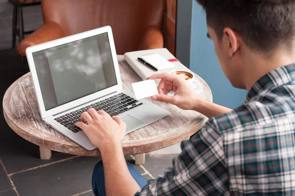 Üzletember nézni nevű kártya rövid idő használ a laptop a fa tabl — Stock Fotó