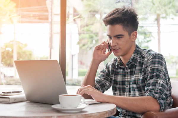 Zakenman met behulp van mobiele telefoon terwijl lookingat laptop op houten — Stockfoto