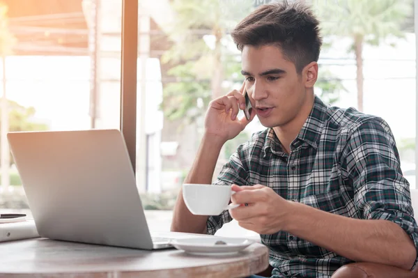 Zakenman met behulp van mobiele telefoon terwijl lookingat laptop op houten — Stockfoto