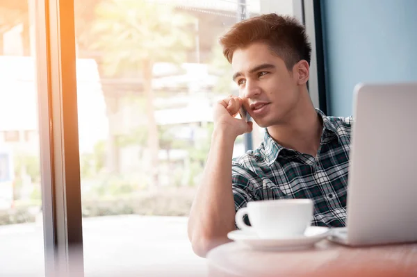 Zakenman met behulp van mobiele telefoon terwijl lookingat laptop op houten — Stockfoto