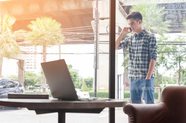 Man met mobiele telefoon met laptop op houten tafel op voorgrond — Stockfoto