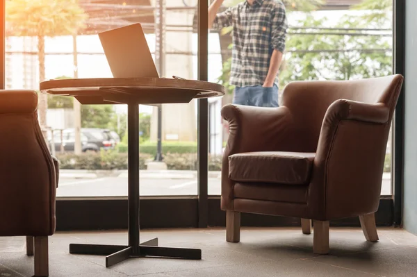 Laptop op houten tafel in koffie winkel met man met mobiele phon — Stockfoto