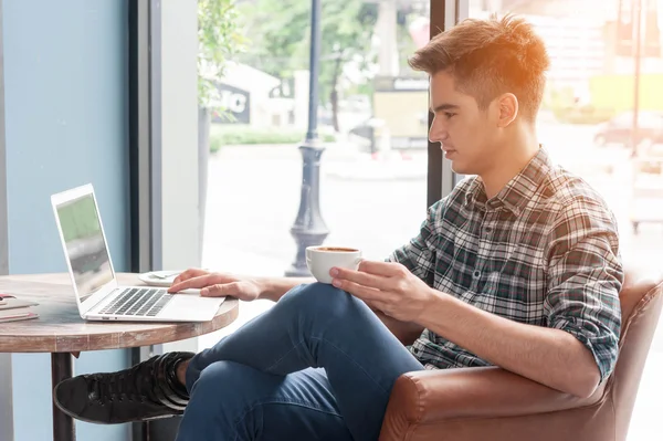 Man drinken koffie met laptop op houten tafel in koffie winkel — Stockfoto