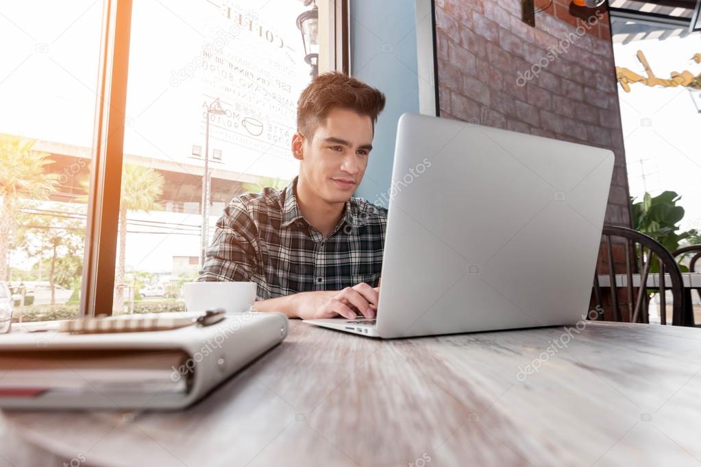 Businessman using laptop on wooden table in coffee shop