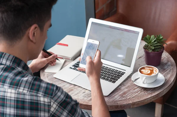 Businessman using smartphone and laptop writing on tablet on woo — Stock Photo, Image