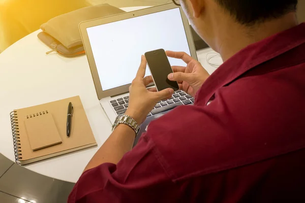 Akıllı telefon kullanarak evden çalışan genç bir adamın kırpılmış atış — Stok fotoğraf