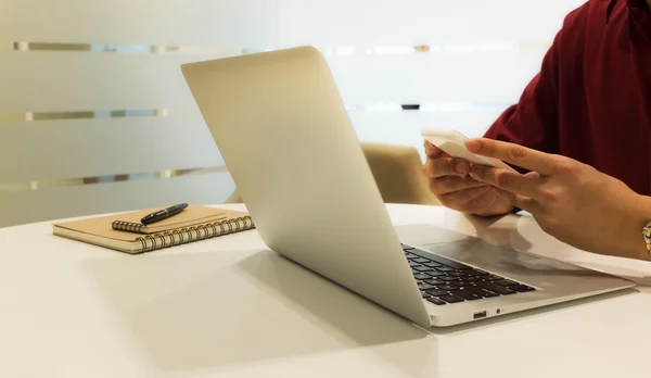 Bijgesneden shot van een jonge man aan het werk vanuit huis met behulp van slimme telefoon — Stockfoto