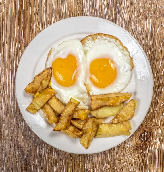 Café da manhã com ovos fritos e batatas fritas em fundo de madeira — Fotografia de Stock