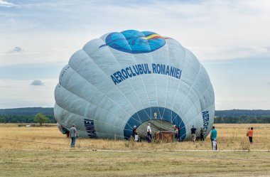 STANESTI, GORJ, ROMANIA - 28 Ağustos 2021: Havacılık mitinginde sıcak hava balonu, Stanesti havalimanı, Gorj, Romanya. Mürettebat balonu şişirmeye hazırlanıyor.