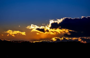 Bulutlu gökyüzü ile dramatik gün batımı arkaplanı.