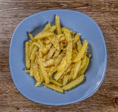 Ahşap arka plan üzerinde plaka üzerinde peynir ile kızarmış patates