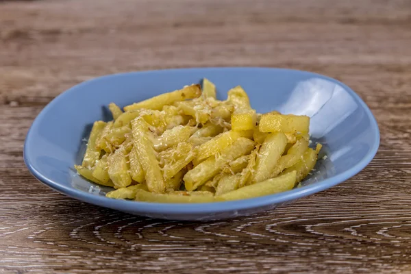 Batatas fritas com queijo no prato em fundo de madeira — Fotografia de Stock