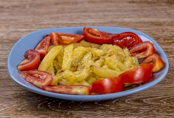 Batatas fritas com tomate e queijo no prato em fundo de madeira — Fotografia de Stock