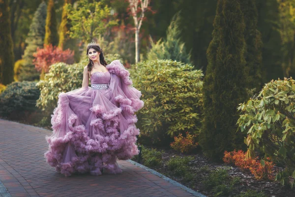 Femme avec une couronne sur la tête marche dans le parc . — Photo