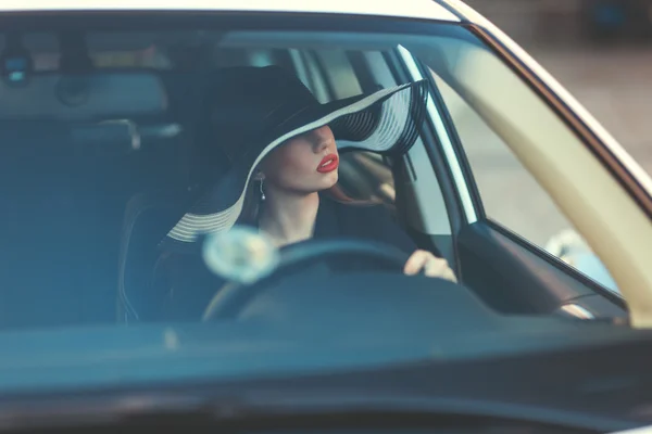 Vrouw in de hoed zit achter het stuur van een auto. — Stockfoto