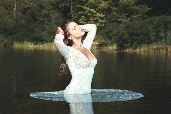 Kvinna i en vit klänning stående i vatten. — Stockfoto