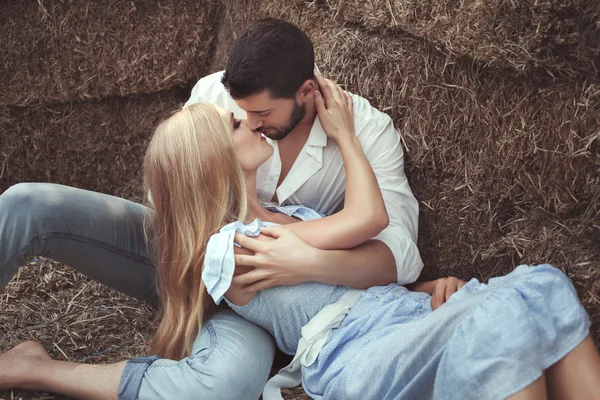 Man die een vrouw kussen in de hooizolder. — Stockfoto